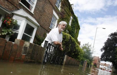 最も洪水の被害がひどい英国中部のテュークスベリーで、浸水した自宅から外を眺める男性＝２４日、ロイター提供