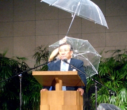 土砂降りの雨の中、野外で福音のメッセージを伝える峯野龍弘牧師＝２９日、東京・淀橋教会で