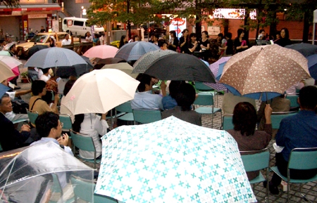 小雨が降るなか、参加者は傘をさしながらコンサートを楽しんだ＝同上